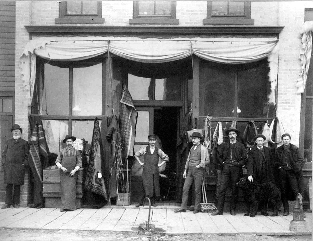 Image: an 1888 photograph of seven men standing in front of the R.M. Johnson Harness Shop in Moorhead. Read below for further details.